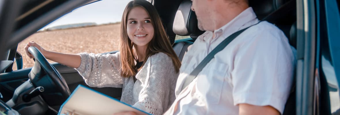Young woman learns to drive from male driving instructor
