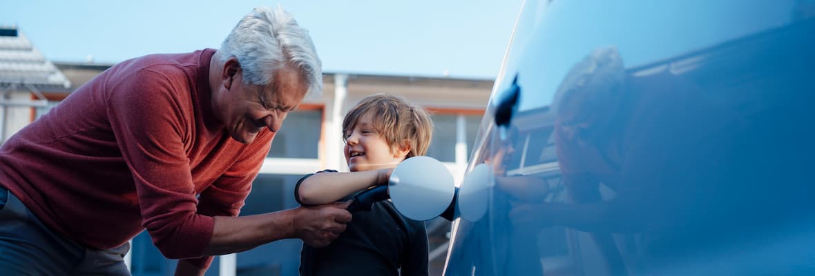 Grandfather and grandson charge electric car