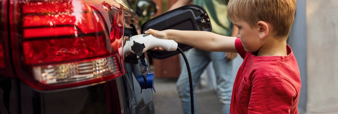 Young boy in red shirt charging electric car