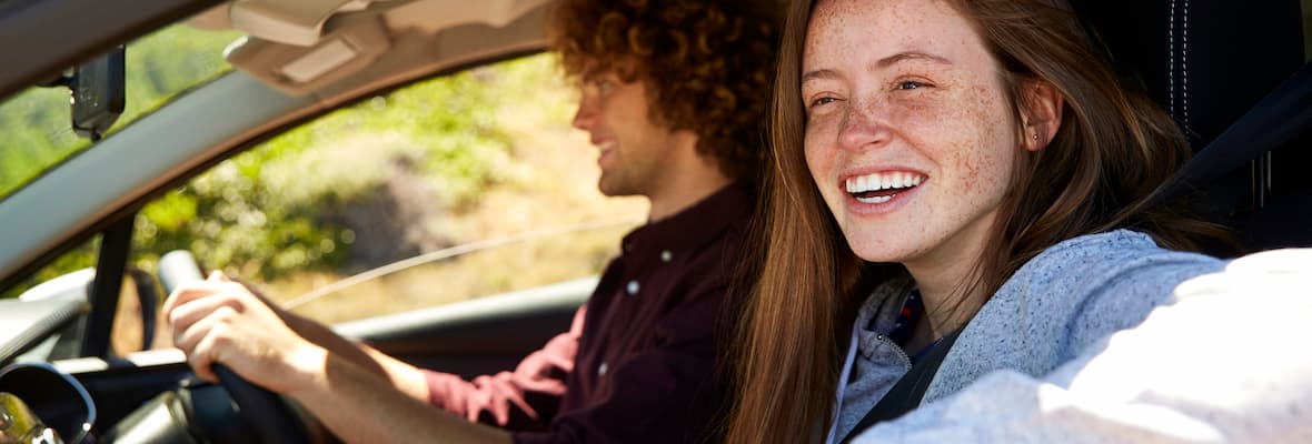 happy couple drive in car along greenery