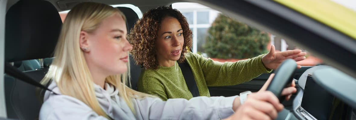 Young woman recieves driving instruction from a supervisor