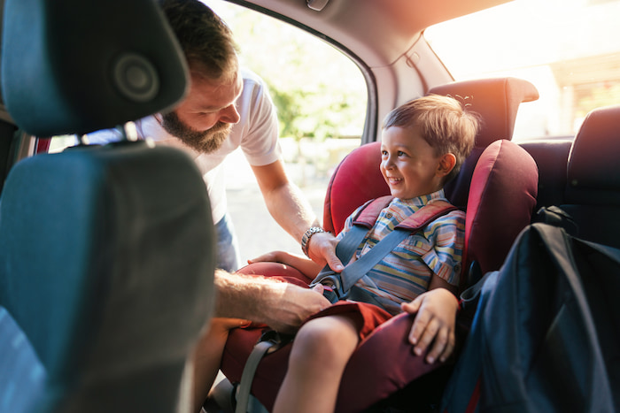 Man buckles his young son into an ISOFIX car seat