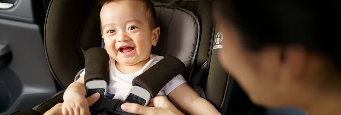 A father buckles his baby boy into a rear facing car seat