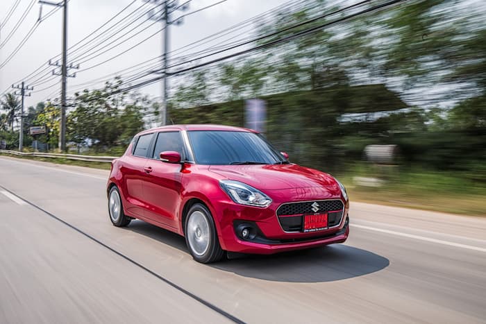 red suzuki swift driving outside on road