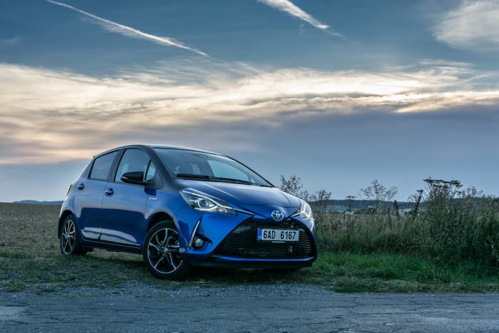 Blue Toyota Yaris is parked on the side of the road at dusk