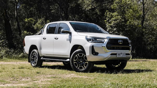 white Toyota Hilux parked on grass outside