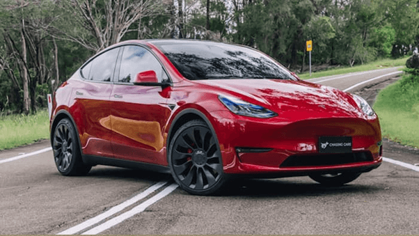 Red tesla model y parked across the road outside