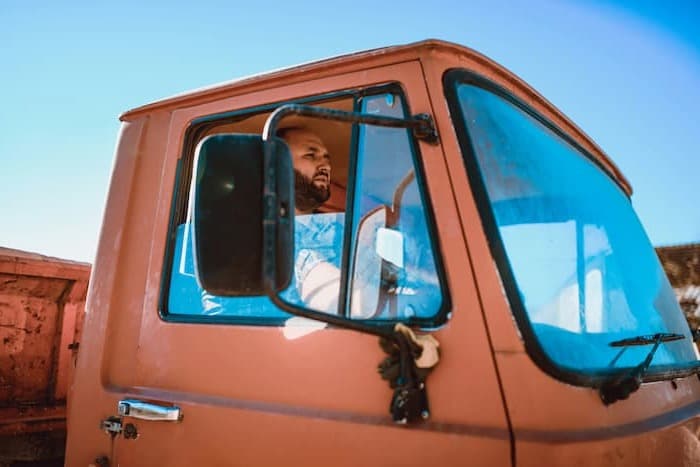 A truck driver checks his side mirror for blind spots while driving.