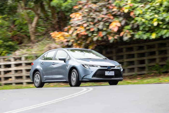 Light blue toyota corolla hybrid driving along winding road