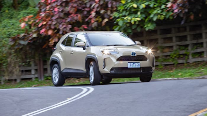 cream coloured Toyota Yaris Cross GXL Hybrid driving on road outside