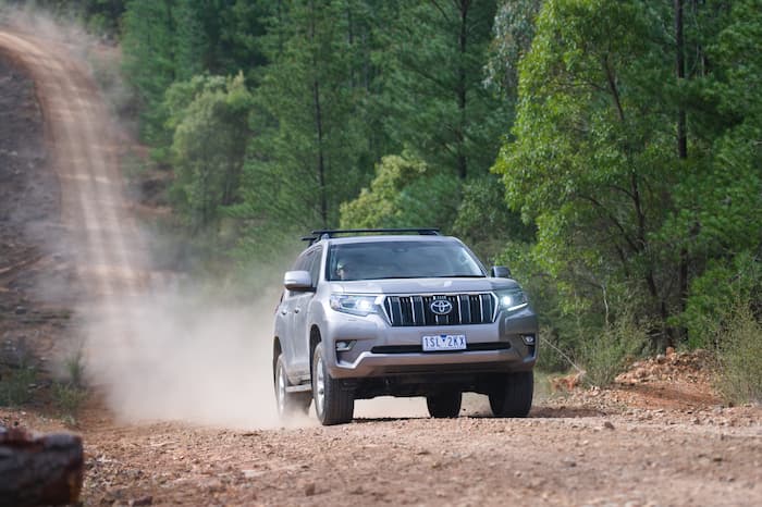 Silver toyota prado driving up dirt road