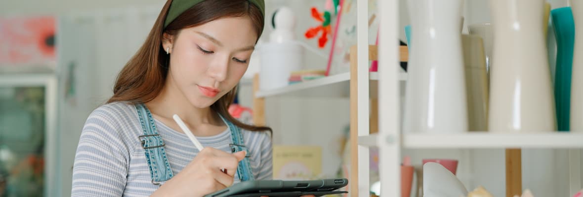 A young woman takes inventory of her personal belongings in her home on a tablet. 