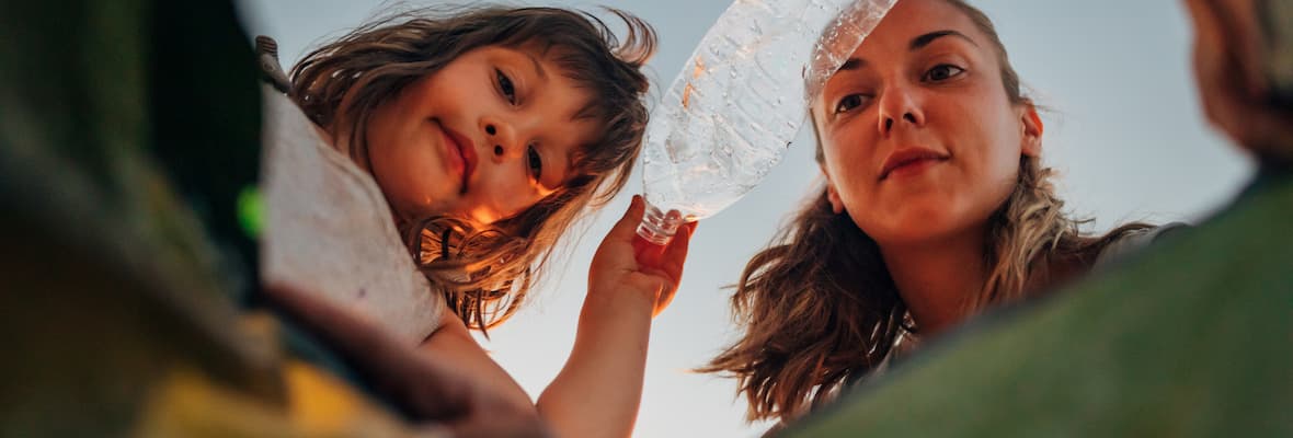 Mother and daughter throw a plastic bottle into a rubbish bin 