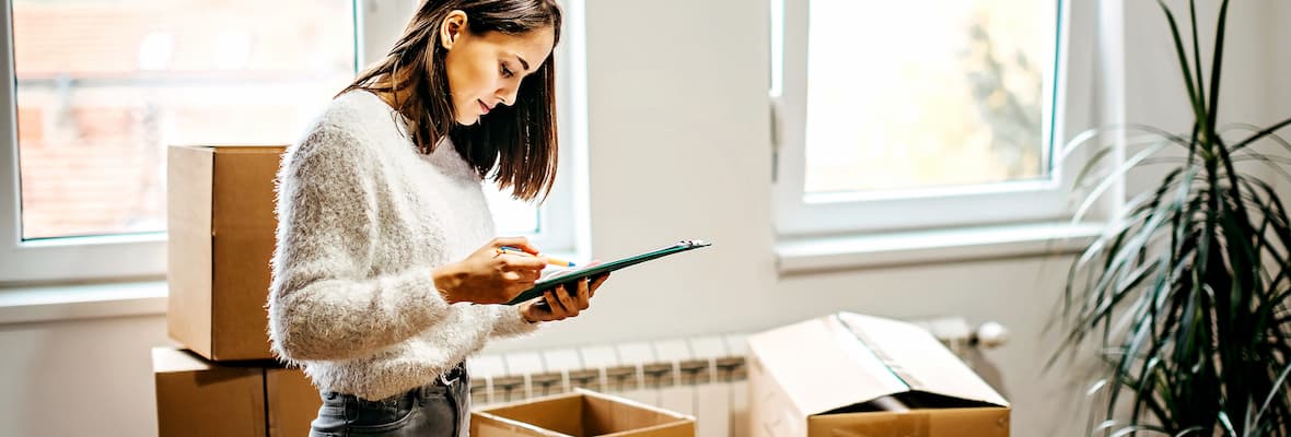 Young woman uses checklist while moving apartments