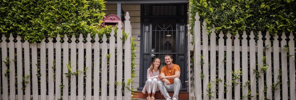  A couple sits on the front steps of their home.