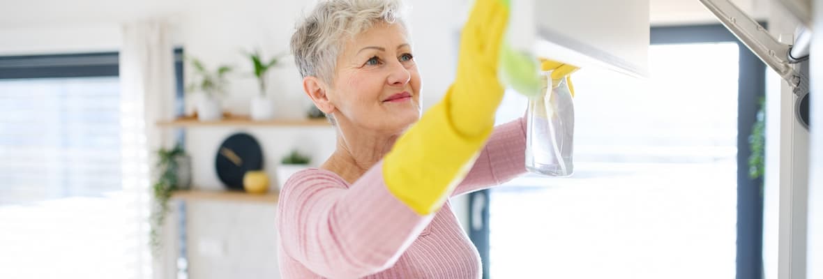 Older woman cleans kitchen cabinets