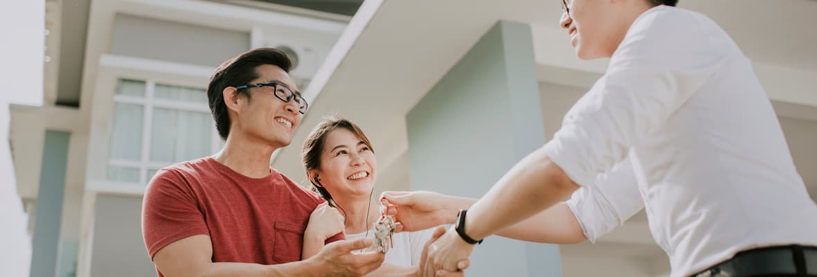 Smiling young couple are handed the keys to their new home