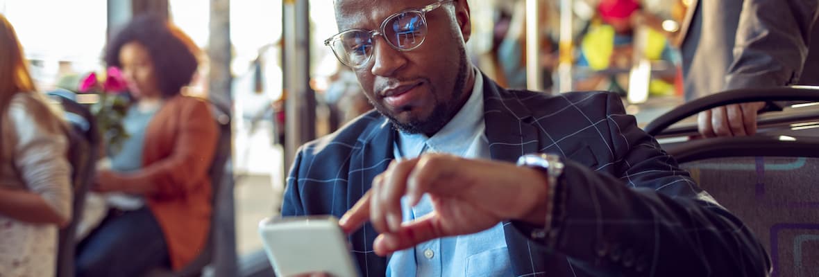 businessman checks phone on bus while commuting to work