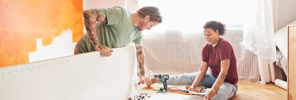 Couple sits on ground to build furniture in home renovation