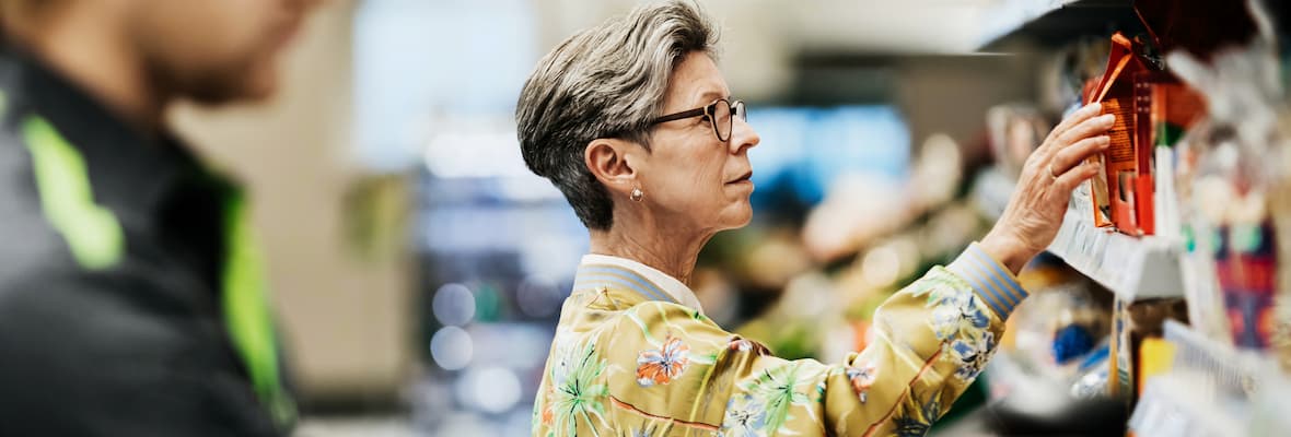 Woman picks packet from a shelf in a supermarket