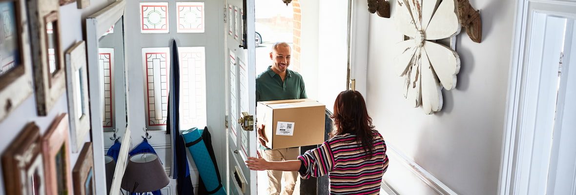 Woman opens door of her home to delivery man with package