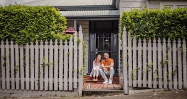  A couple sits on the front steps of their home.