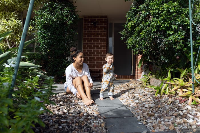 Young Aussie mum sitting outside her house with her toddler daughter