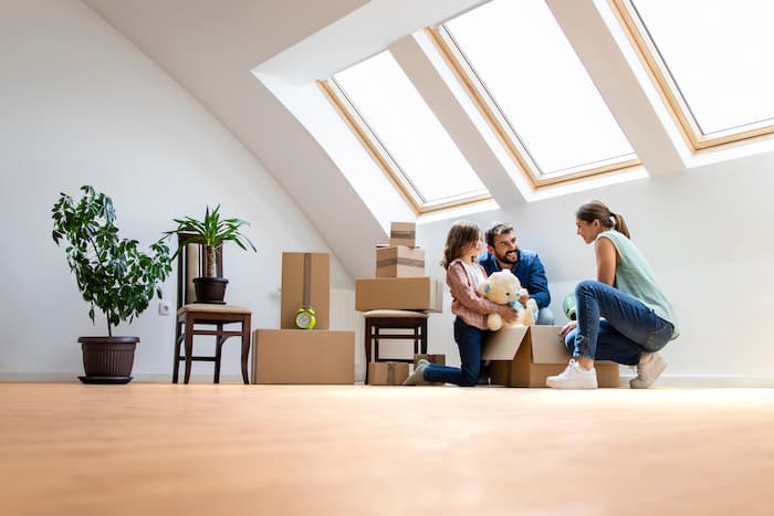 A young family unpacks moving boxes in a modern home with three large skylights.