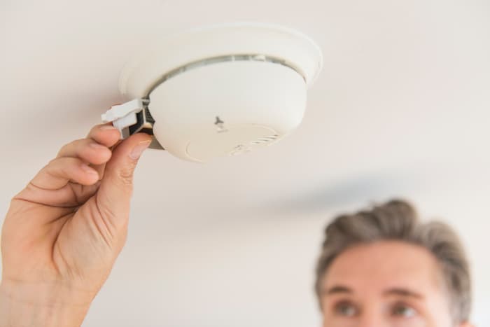 Man opens smoke alarm battery compartment