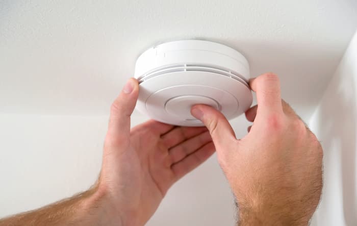 Man tests new smoke alarm batteries by pressing the test button