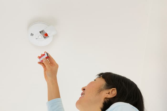 Woman replaces the batteries in a smoke alarm