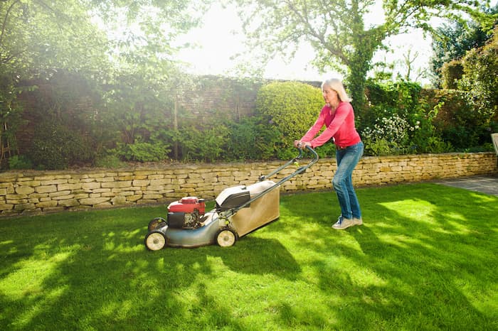 older woman mowing lawn in back yard