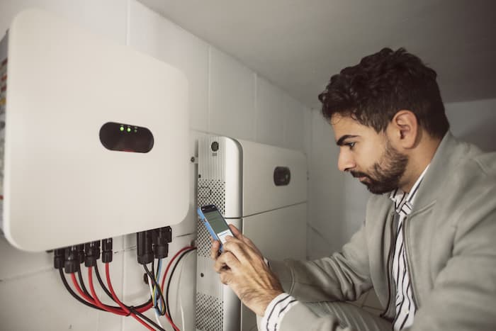 Technical Electrician synchronises the converter and solar battery using a mobile phone