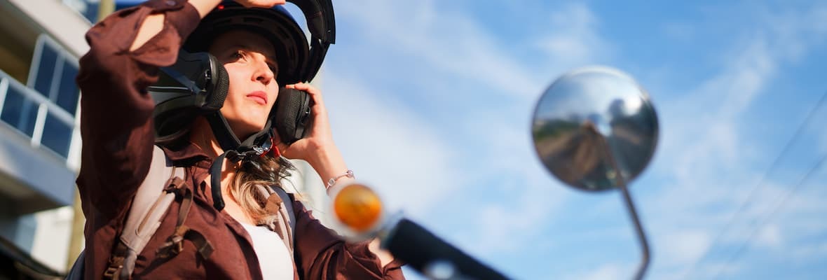 Young female rider puts on a motorcycle helmet