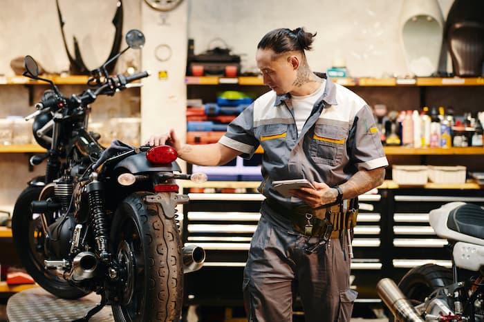 A mechanic performs a pre-purchase inspection for a customer looking to buy a motorcycle.