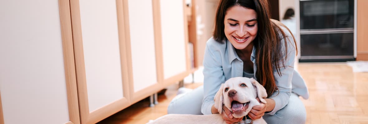 Young woman plays with her dog on the kitchen floor