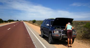 A 4x4 is broken down on the side of an outback road, being checked by the driver