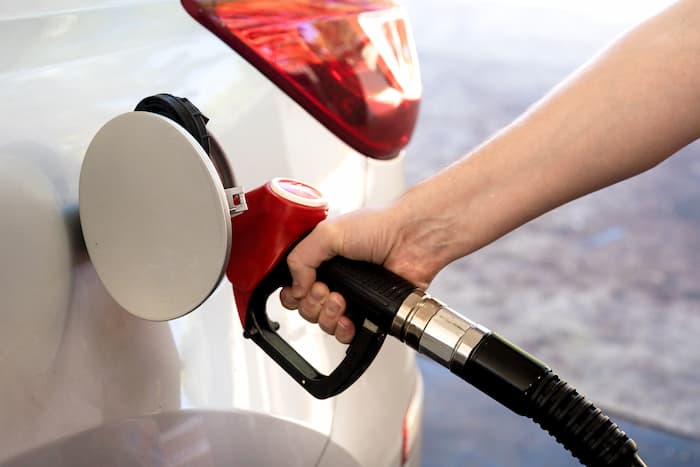 A person refuels their car using a petrol pump at a petrol station in Australia.