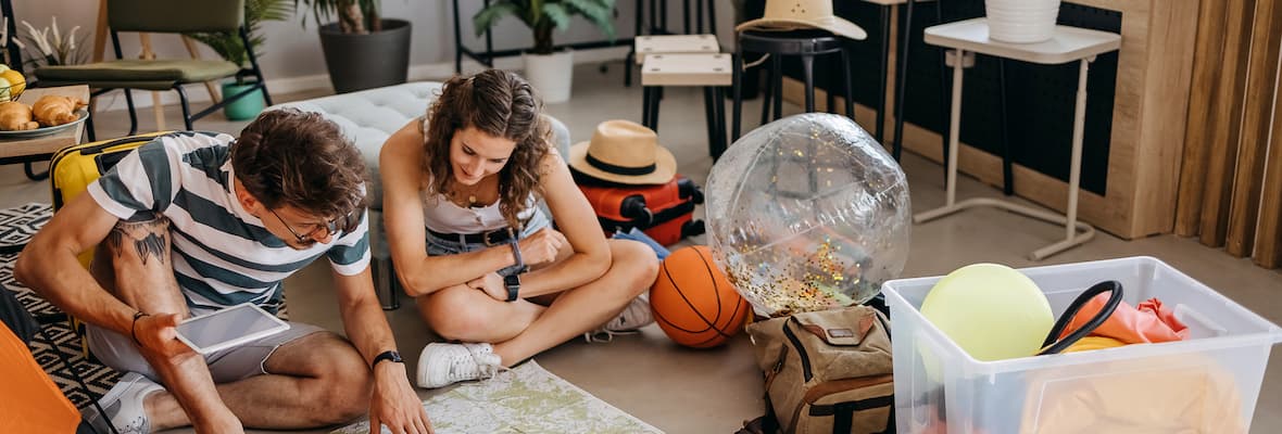 couple sit on floor looking at map planning holiday
