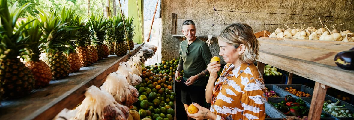 woman and man shop at local fruit grocer while travelling