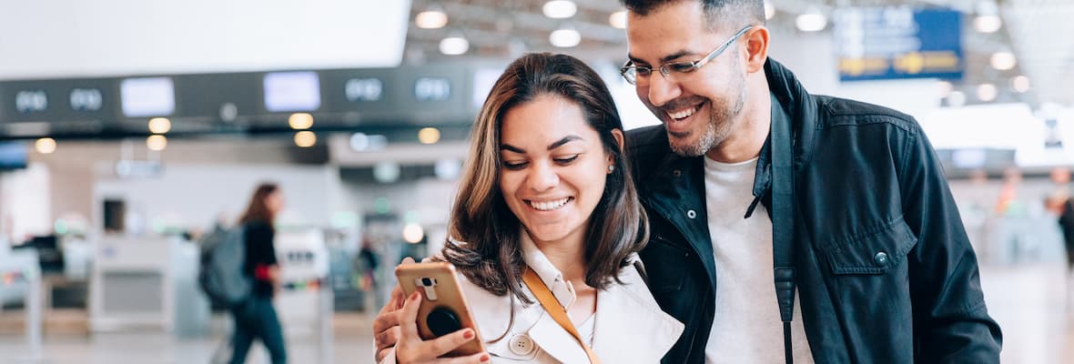 Young couple use a mobile phone at the airport before flying overseas 