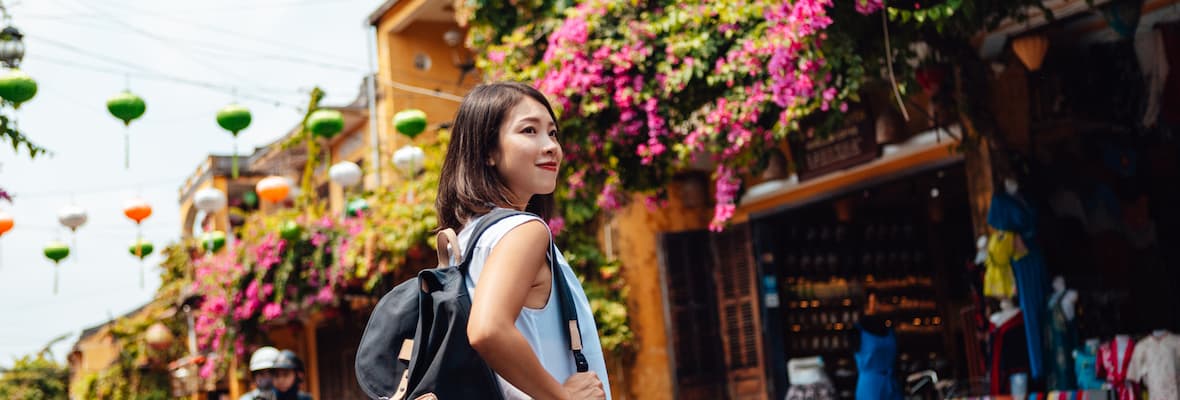 Young woman carrying a backpack walks alongside the local markets in Hoi An.
