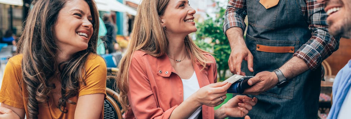 Woman pays for lunch with friends in a cafe using a travel card