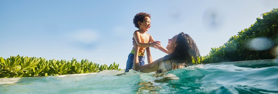 mum and son swimming in ocean together on holiday