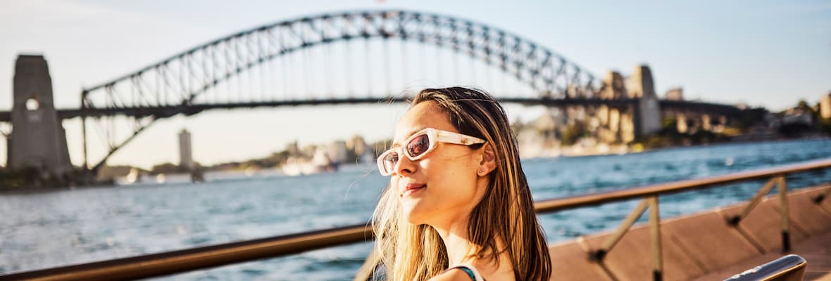 Solo traveller sits across from the Sydney Harbour Bridge