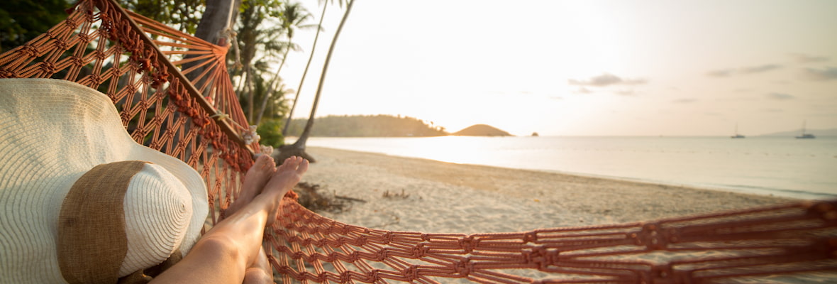 Young woman on Thailand tropical beach relaxing in hammock at sunset