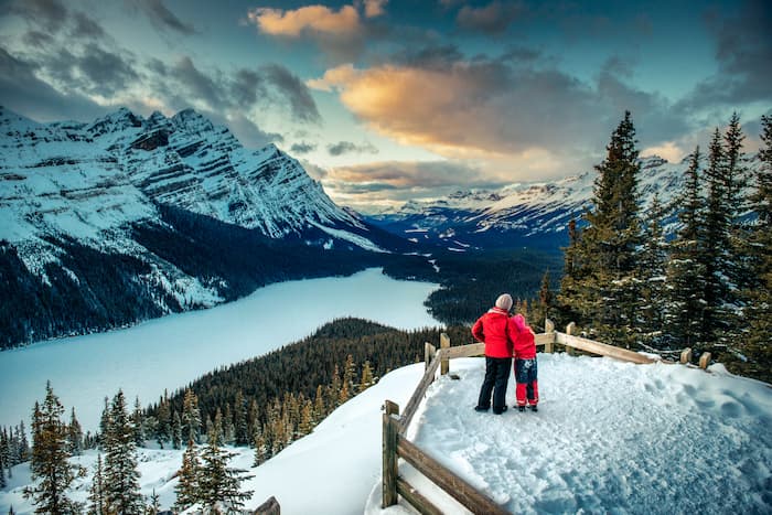 A young couple wearing red jackets look over Banff National Park while it's snowing.