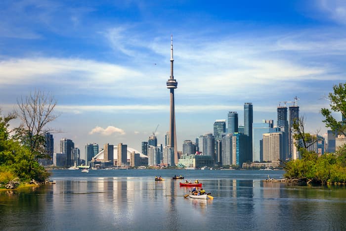 Tourists canoe on Lake Ontario towards the Toronto skyline.