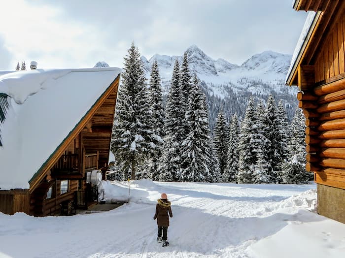 A young woman walks between two wood cabins in the snow in Fernie, British Columbia.