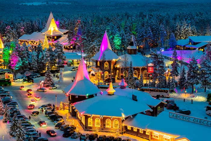 A winter village is lit up with dazzling rainbow lights in the arctic region of Lapland